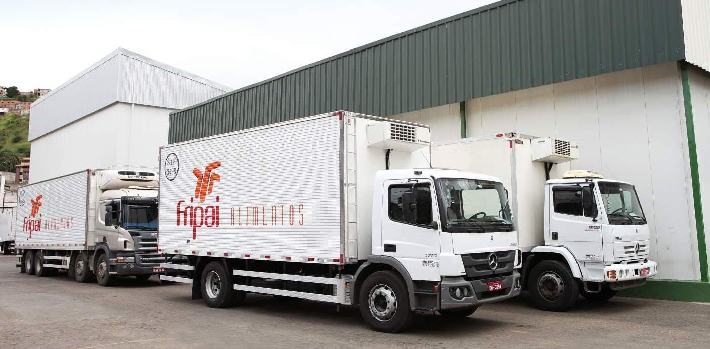 Frota de caminhões refrigerados com a marca Fripai no pátio da planta.